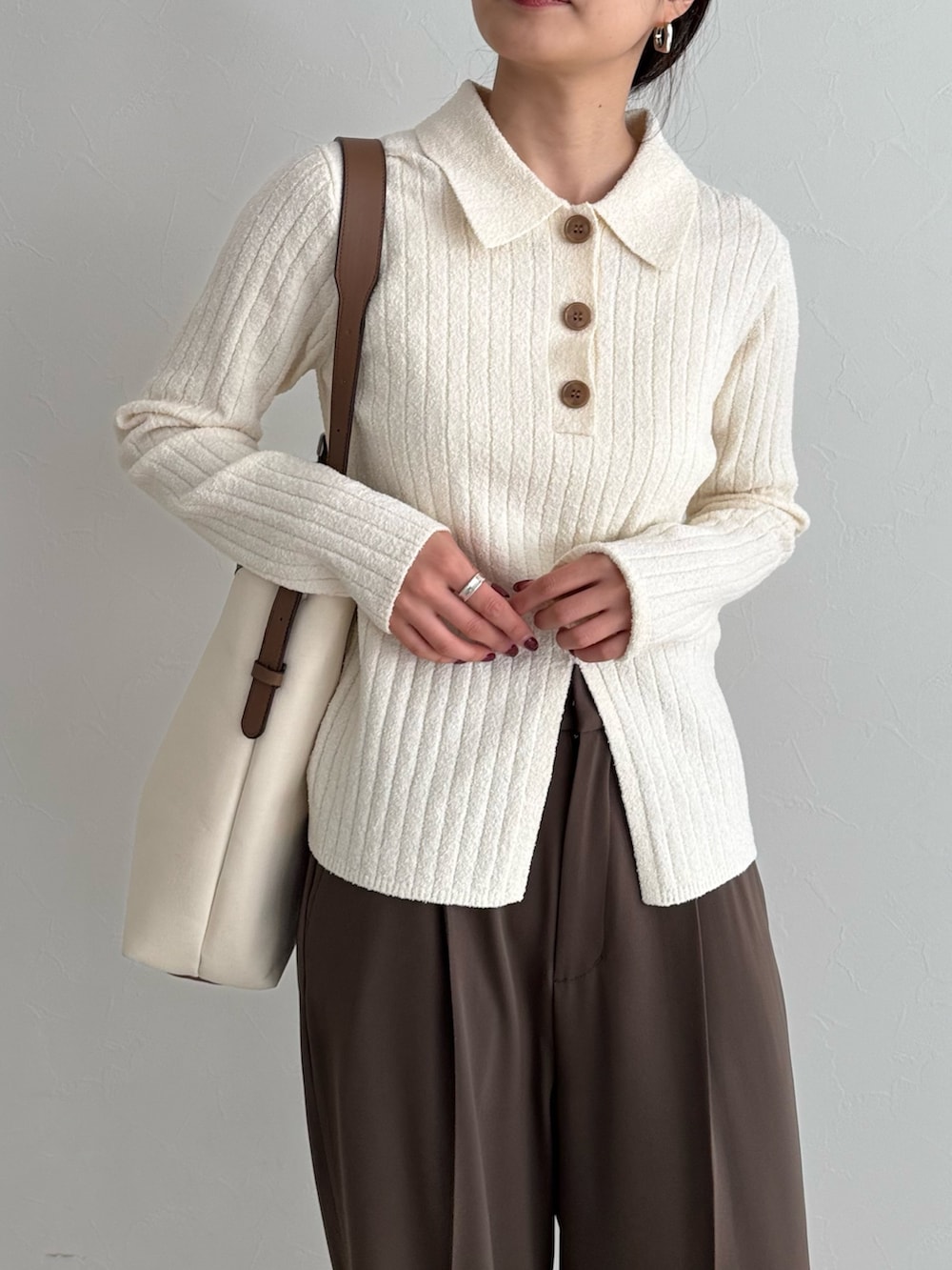 ホワイト系のニット/セーター、ブラウン系のスラックス、ホワイト系のショルダーバッグを着用したレディースの冬コーディネートの3枚目の写真