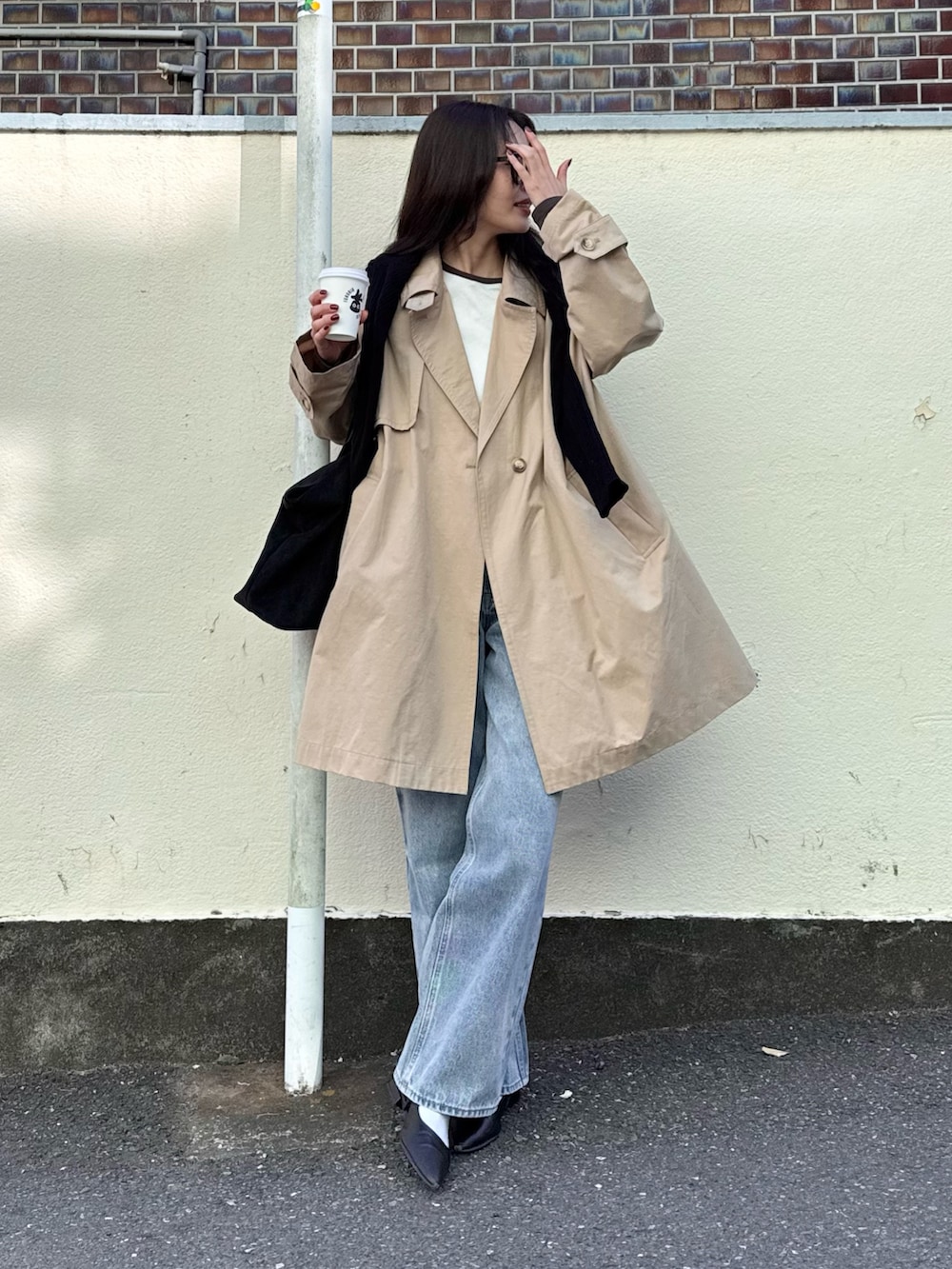 ベージュ系のトレンチコート、ブルー系のデニムパンツ、ブラック系のトートバッグを着用したレディースの冬コーディネートの2枚目の写真