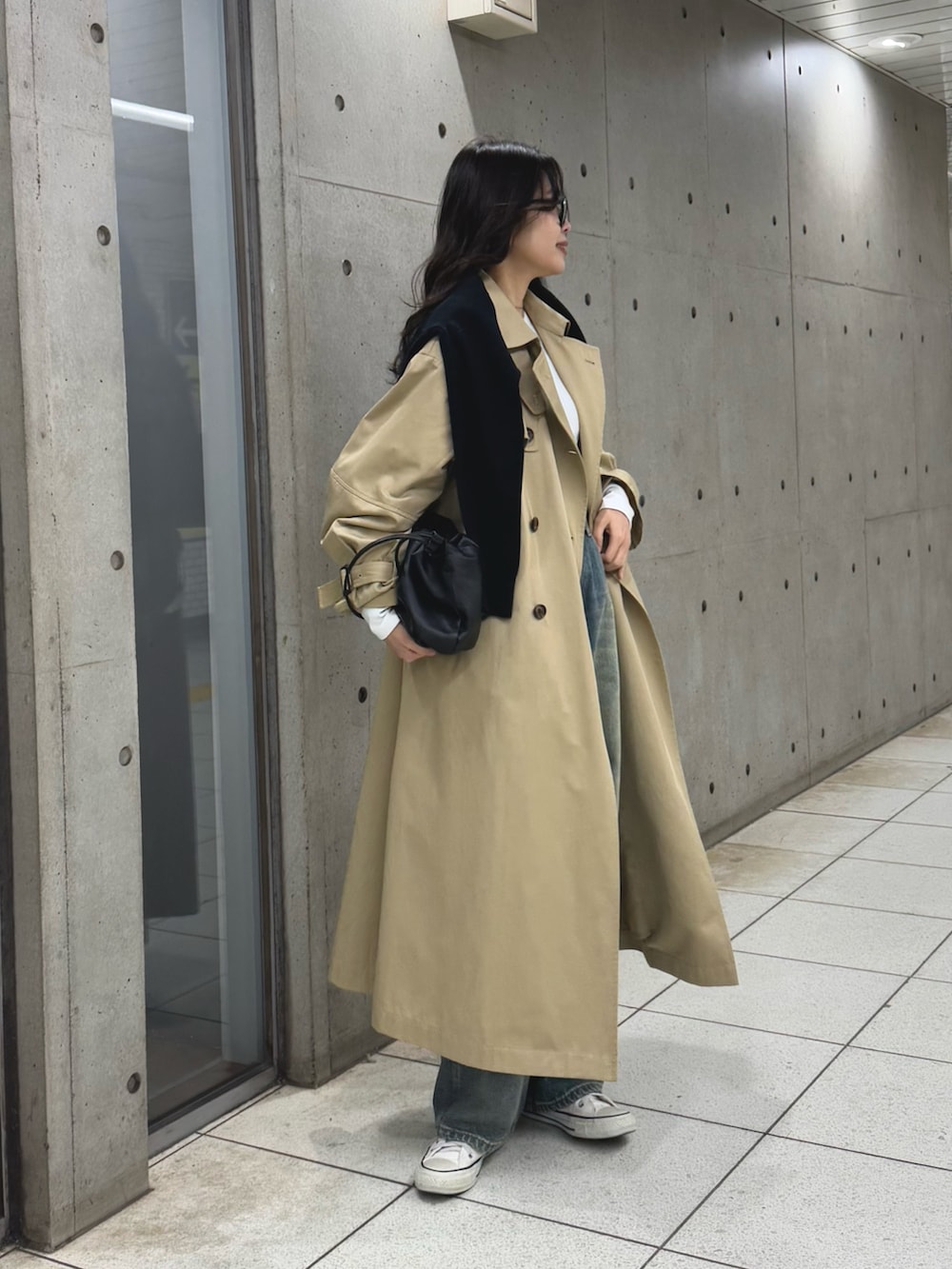 ベージュ系のトレンチコート、ブルー系のデニムパンツ、ブラック系のショルダーバッグを着用したレディースの冬コーディネートの4枚目の写真