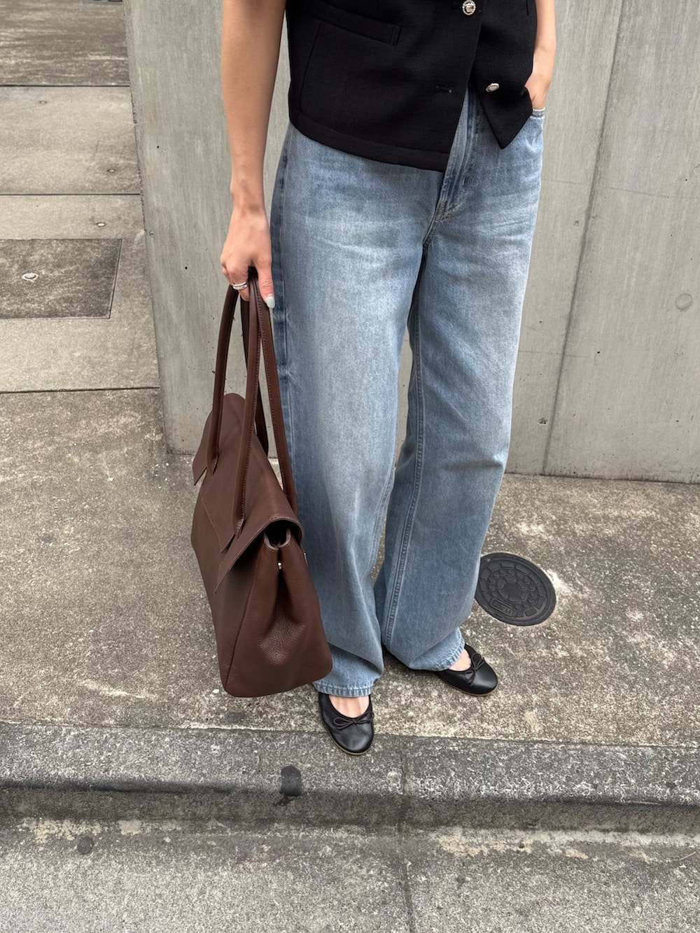 ブラック系のノーカラージャケット、ブルー系のデニムパンツ、ブラウン系のショルダーバッグを着用したレディースの春コーディネートの5枚目の写真