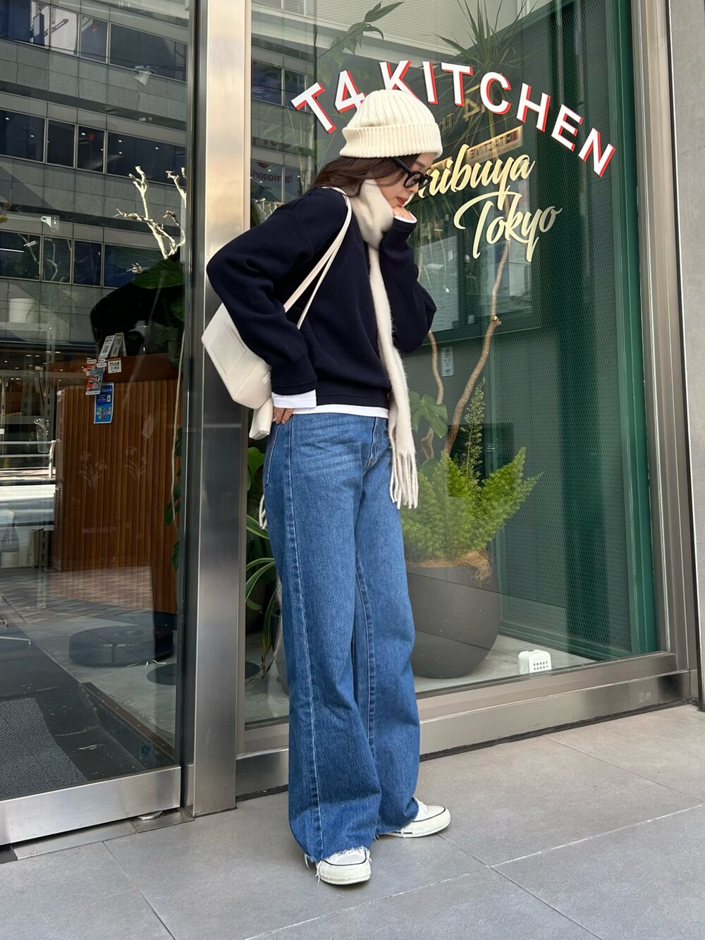 ブルー系のニット/セーター、ブルー系のデニムパンツ、ホワイト系のストール/ショールを着用したレディースの冬コーディネートの2枚目の写真