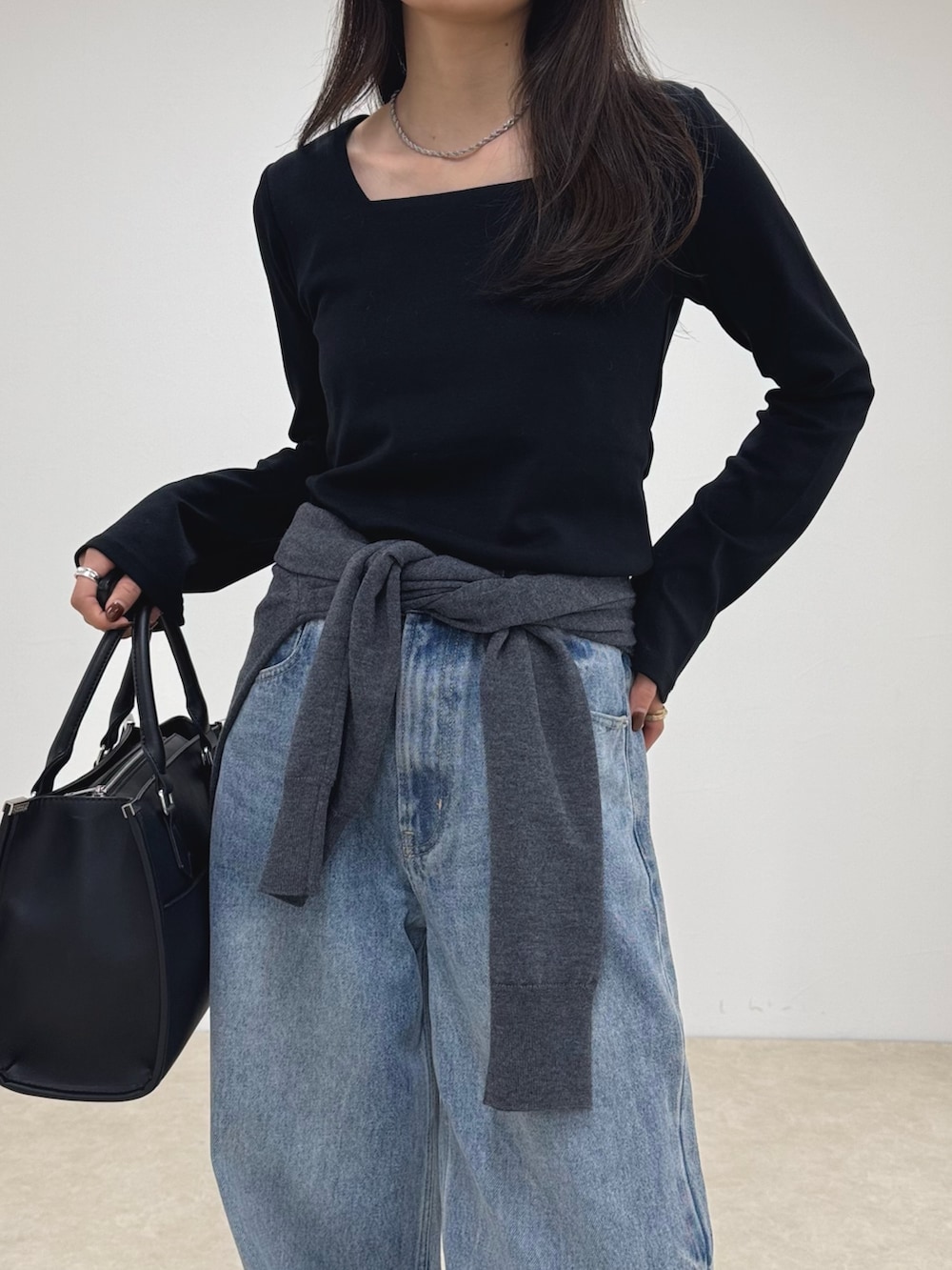 ブラック系のTシャツ/カットソー、ブルー系のデニムパンツ、ブラック系のボストンバッグを着用したレディースの秋コーディネートの5枚目の写真