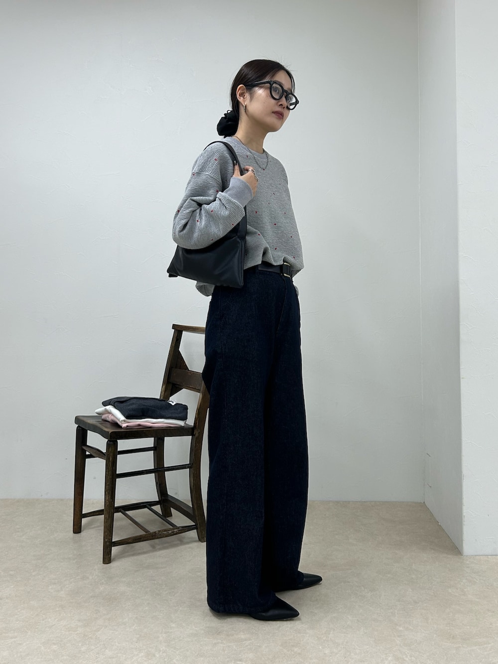 グレー系のスウェット、ブルー系のデニムパンツ、ブラック系のショルダーバッグを着用したレディースの秋コーディネートの2枚目の写真