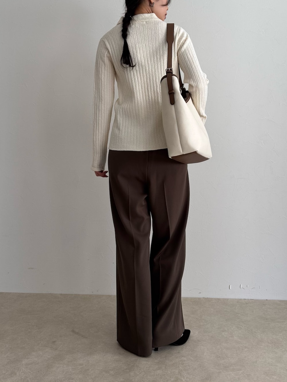 ホワイト系のニット/セーター、ブラウン系のスラックス、ホワイト系のショルダーバッグを着用したレディースの冬コーディネートの2枚目の写真