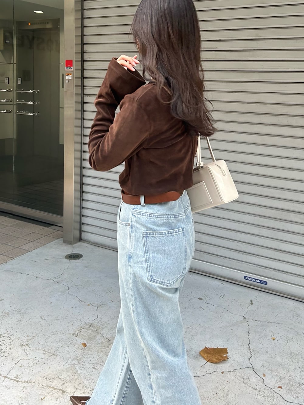 ブラウン系のTシャツ/カットソー、ブルー系のデニムパンツ、ホワイト系のボストンバッグを着用したレディースの冬コーディネートの4枚目の写真