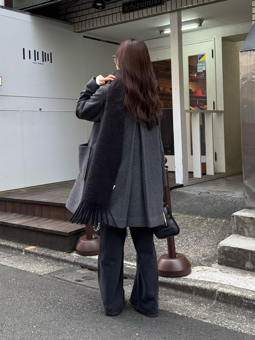 グレー系のダッフルコート、ブラック系のショルダーバッグ、ブラック系のデニムパンツを着用したレディースの秋コーディネートの4枚目の写真