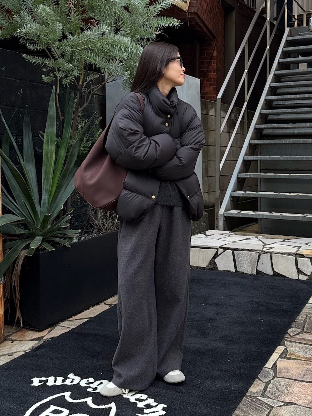 ブラック系のダウンジャケット/コート、ブラック系のその他パンツ、グレー系のニット/セーターを着用したレディースの冬コーディネートの2枚目の写真