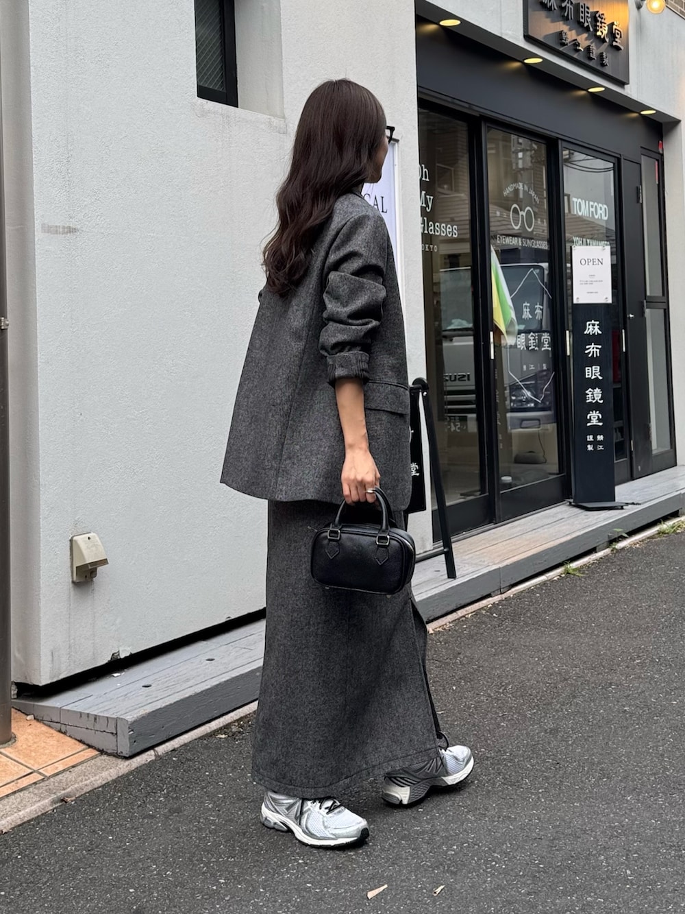 グレー系のテーラードジャケット、グレー系のスカート、ブラック系のショルダーバッグを着用したレディースの秋コーディネートの3枚目の写真