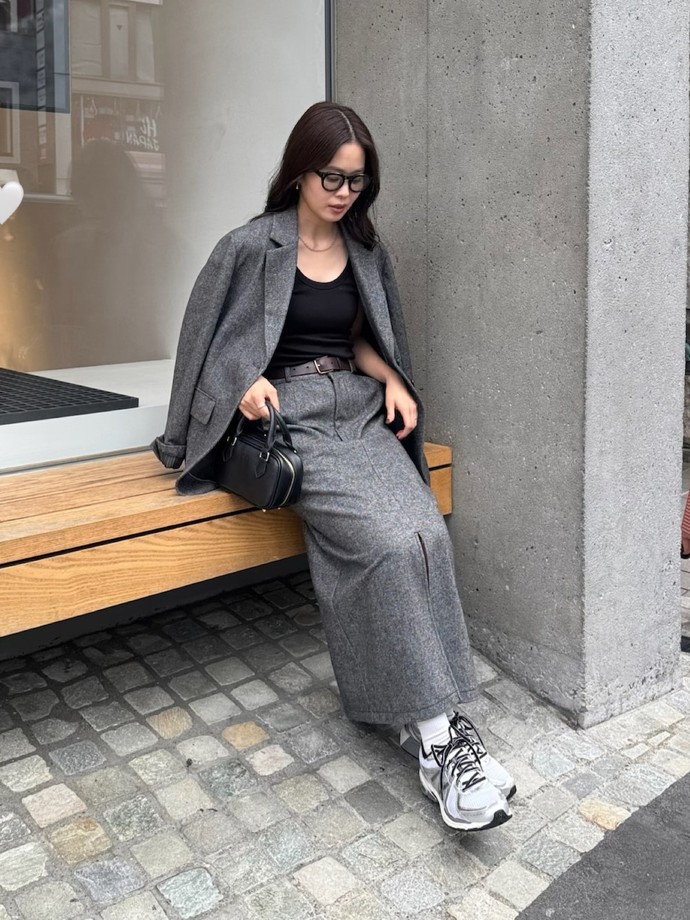 グレー系のテーラードジャケット、グレー系のスカート、ブラック系のショルダーバッグを着用したレディースの秋コーディネートの4枚目の写真