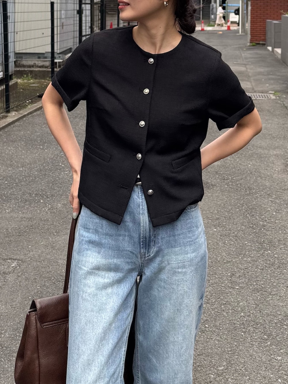 ブラック系のノーカラージャケット、ブルー系のデニムパンツ、ブラウン系のショルダーバッグを着用したレディースの春コーディネートの3枚目の写真