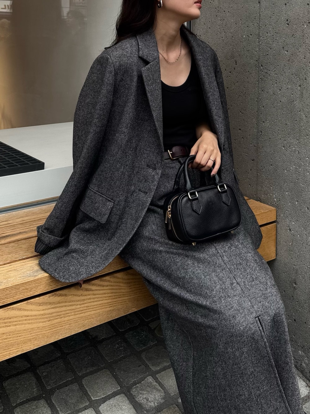 グレー系のテーラードジャケット、グレー系のスカート、ブラック系のショルダーバッグを着用したレディースの秋コーディネートの5枚目の写真