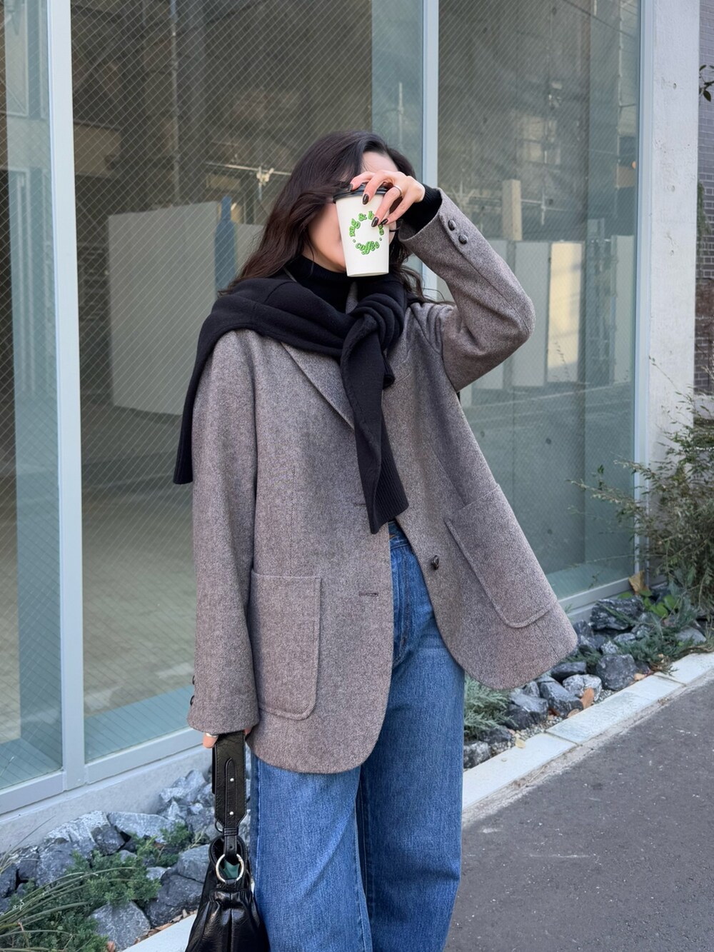 ブルー系のデニムパンツ、ブラウン系のテーラードジャケット、ブラック系のニット/セーターを着用したレディースの冬コーディネートの2枚目の写真