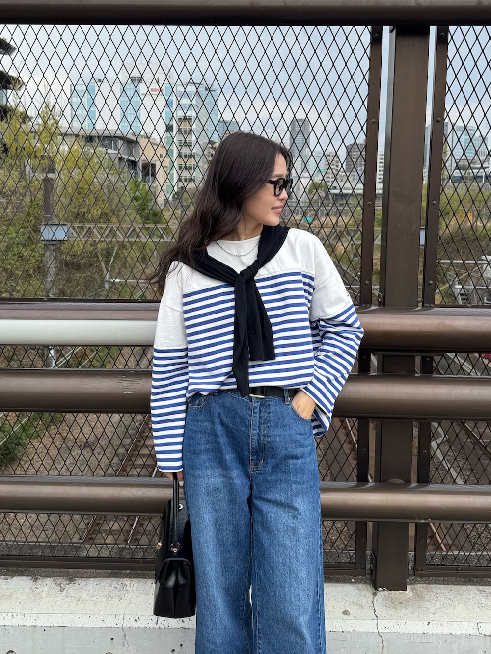 ブルー系のTシャツ/カットソー、ブルー系のデニムパンツ、ブラック系のカーディガン/ボレロを着用したレディースの春コーディネートの3枚目の写真