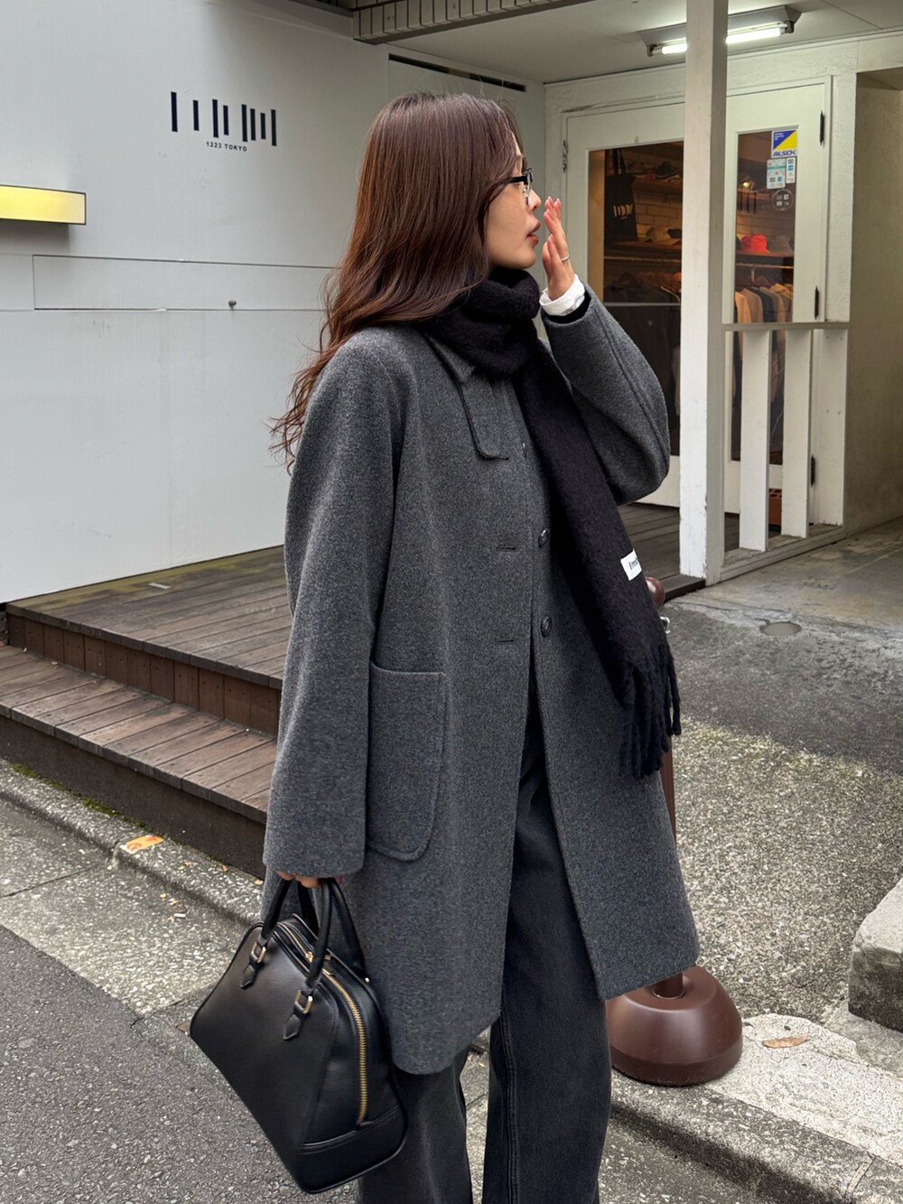 グレー系のダッフルコート、ブラック系のショルダーバッグ、ブラック系のデニムパンツを着用したレディースの秋コーディネートの3枚目の写真