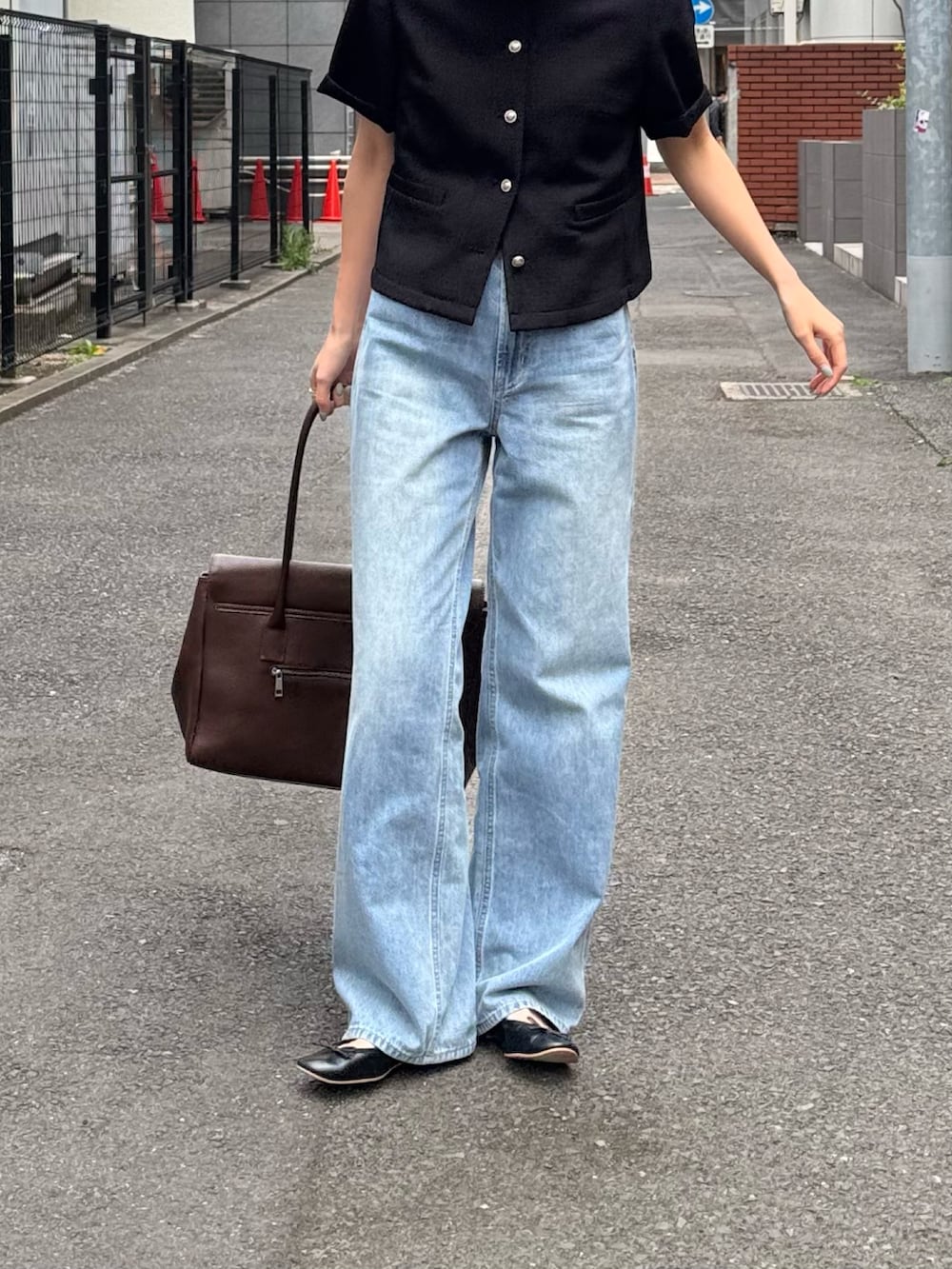 ブラック系のノーカラージャケット、ブルー系のデニムパンツ、ブラウン系のショルダーバッグを着用したレディースの春コーディネートの4枚目の写真