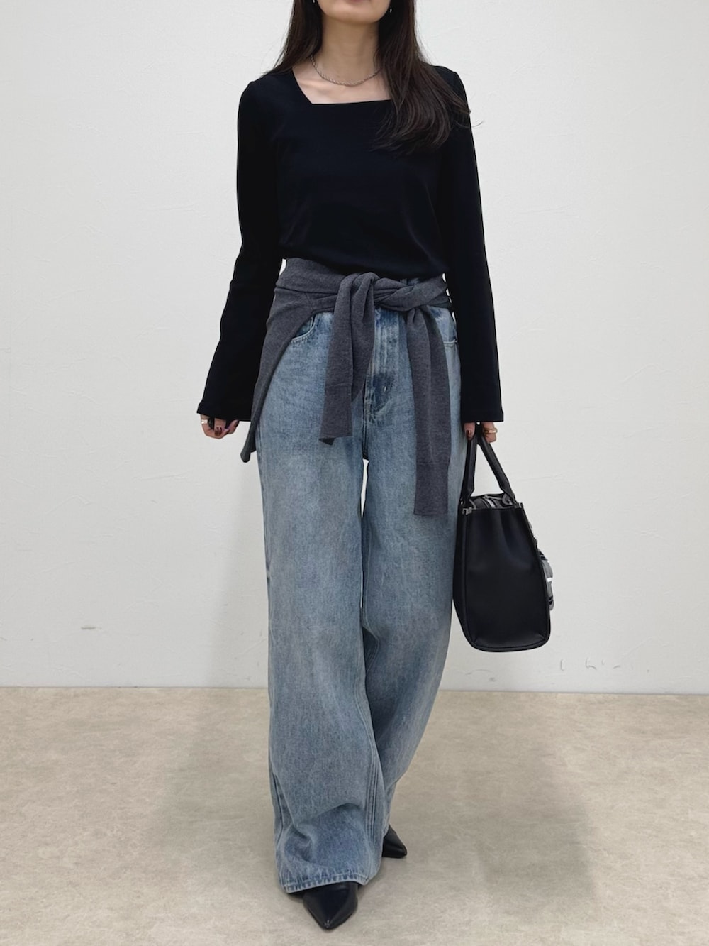 ブラック系のTシャツ/カットソー、ブルー系のデニムパンツ、ブラック系のボストンバッグを着用したレディースの秋コーディネートの2枚目の写真