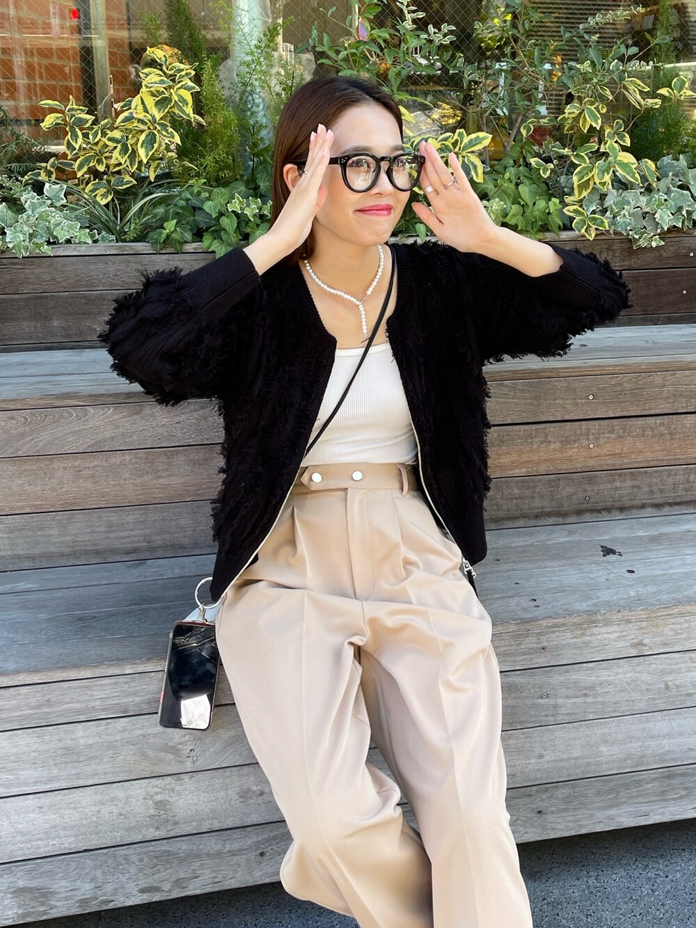 ベージュ系のスラックス、ブラック系のカーディガン/ボレロを着用したレディースの秋コーディネートの2枚目の写真