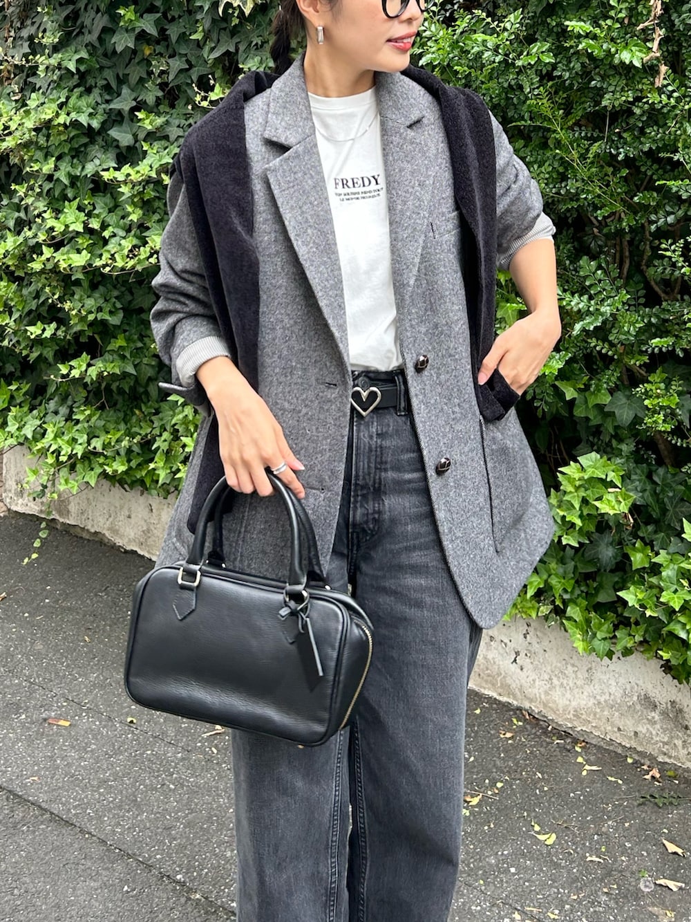 ブラウン系のテーラードジャケット、ブラック系のハンドバッグ、ブラック系のカーディガン/ボレロを着用したレディースの秋コーディネートの2枚目の写真