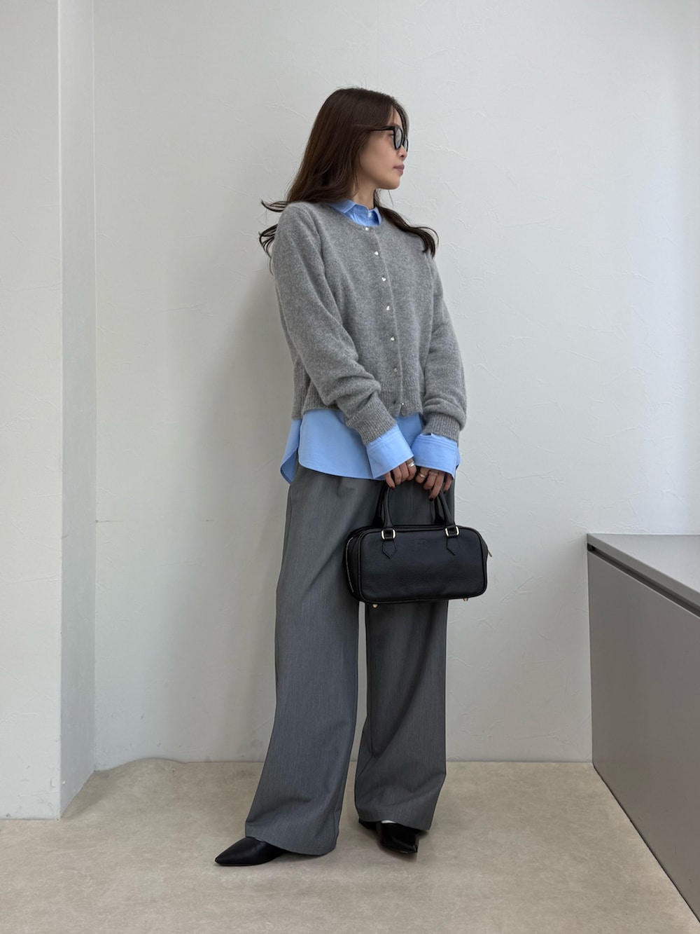 グレー系のカーディガン/ボレロ、ブルー系のシャツ/ブラウス、ブラック系のボストンバッグを着用したレディースの秋コーディネートの2枚目の写真