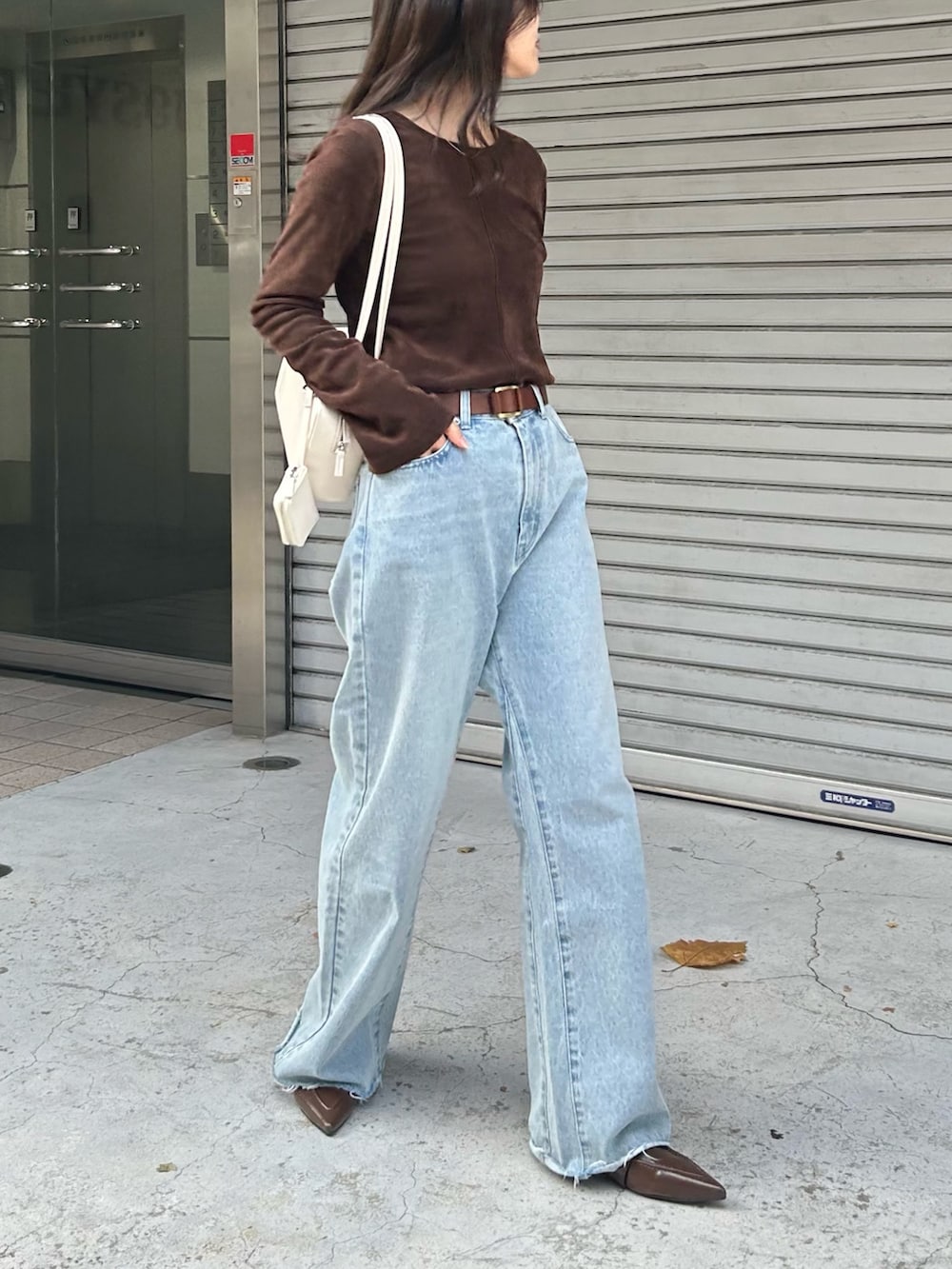ブラウン系のTシャツ/カットソー、ブルー系のデニムパンツ、ホワイト系のボストンバッグを着用したレディースの冬コーディネートの2枚目の写真