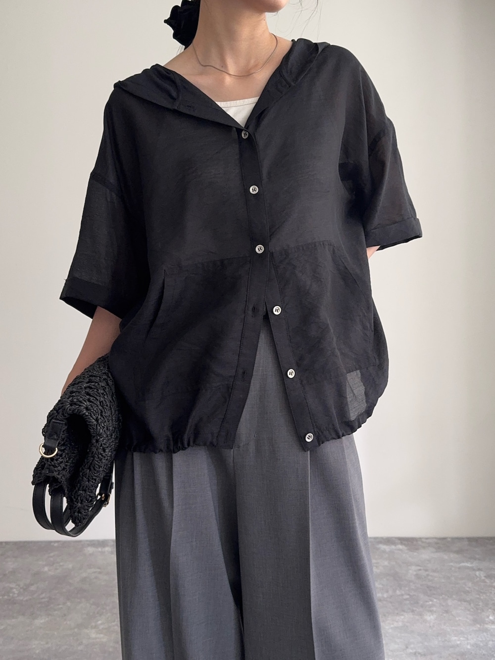 ブラック系のシャツ/ブラウス、グレー系のスラックス、ブラック系のかごバッグを着用したレディースの夏コーディネートの4枚目の写真