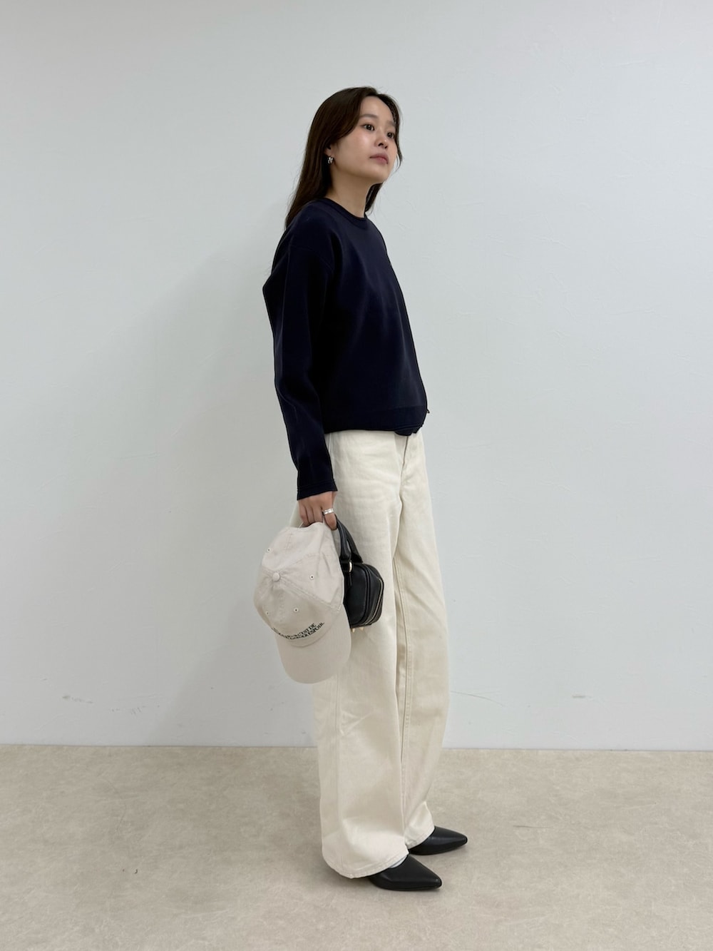 ブルー系のニット/セーター、ホワイト系のデニムパンツ、ホワイト系のキャップを着用したレディースの夏コーディネートの2枚目の写真