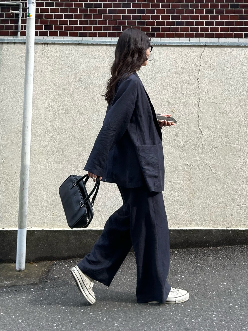 ブルー系のテーラードジャケット、ブルー系のその他パンツ、ブラック系のショルダーバッグを着用したレディースの春コーディネートの2枚目の写真