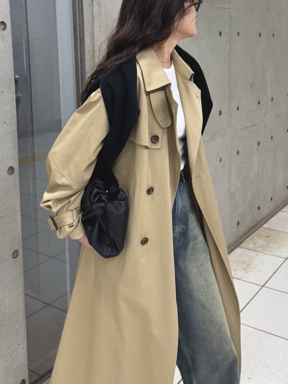 ベージュ系のトレンチコート、ブルー系のデニムパンツ、ブラック系のショルダーバッグを着用したレディースの冬コーディネートの3枚目の写真