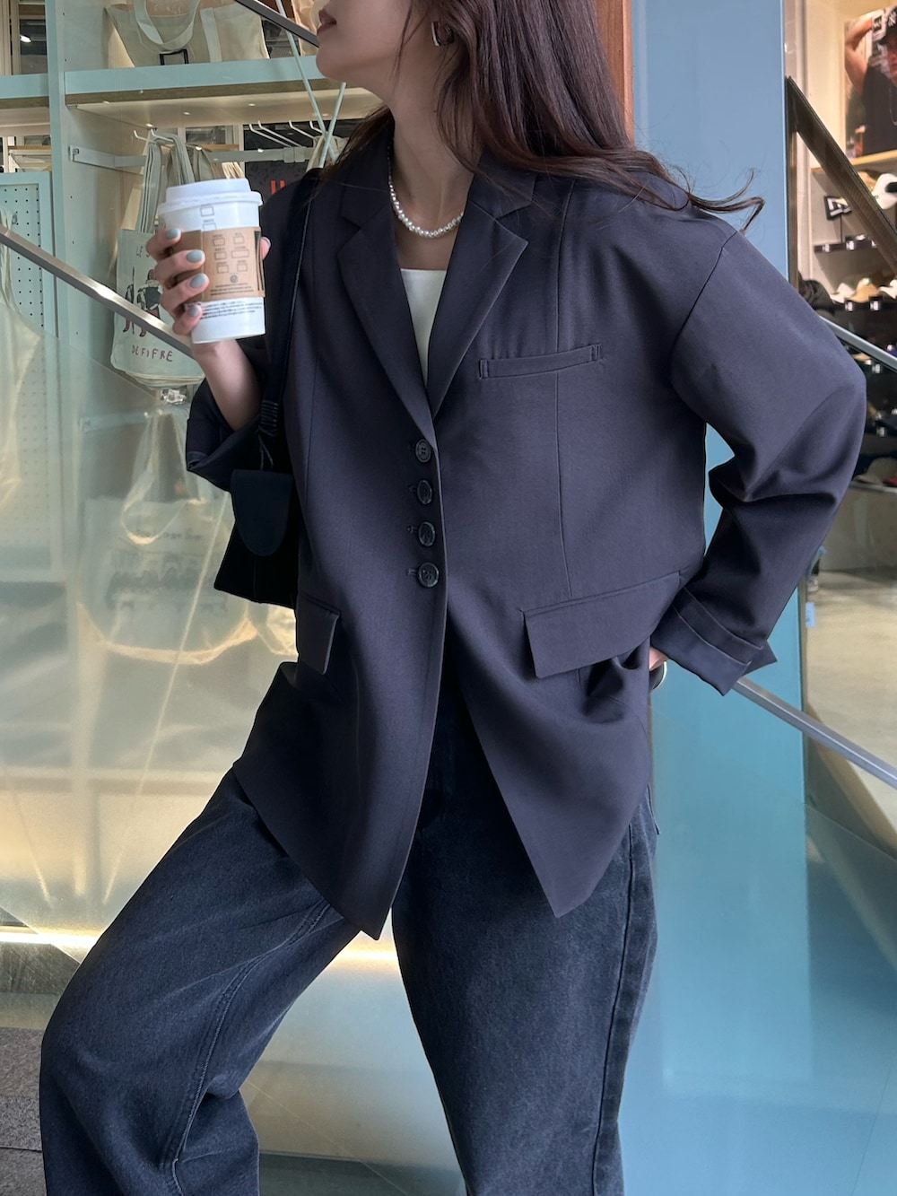 グレー系のテーラードジャケット、ブラック系のデニムパンツを着用したレディースの冬コーディネートの3枚目の写真