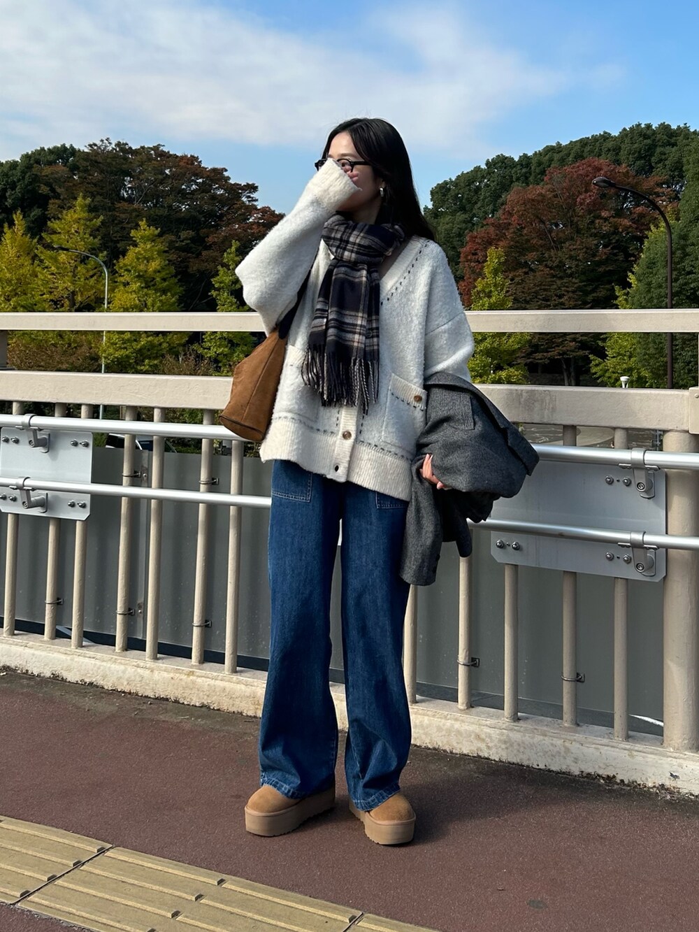 ホワイト系のカーディガン/ボレロ、ブルー系のデニムパンツ、ブラウン系のブーツを着用したレディースの秋コーディネートの2枚目の写真