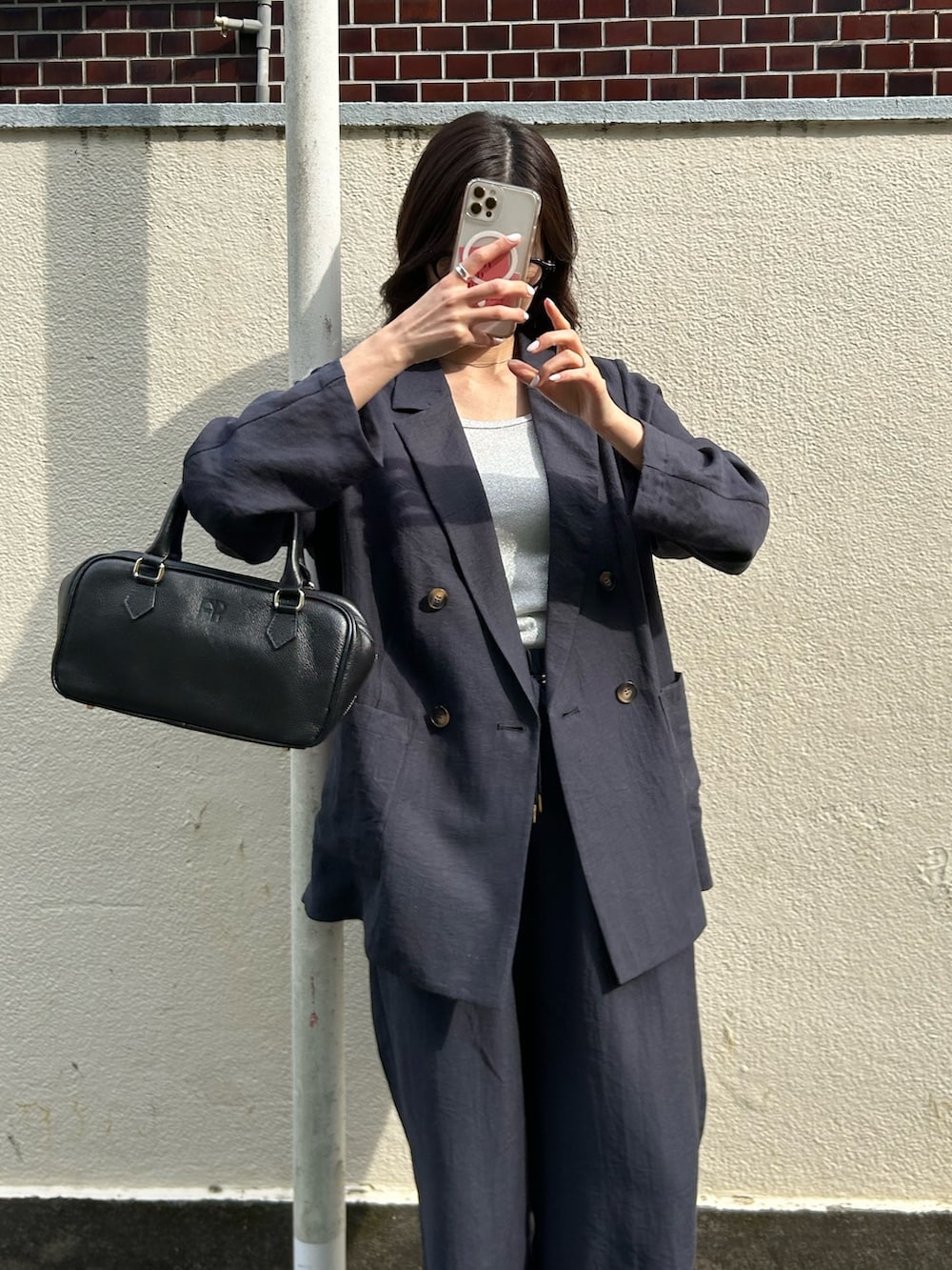 ブルー系のテーラードジャケット、ブルー系のその他パンツ、ブラック系のショルダーバッグを着用したレディースの春コーディネートの3枚目の写真