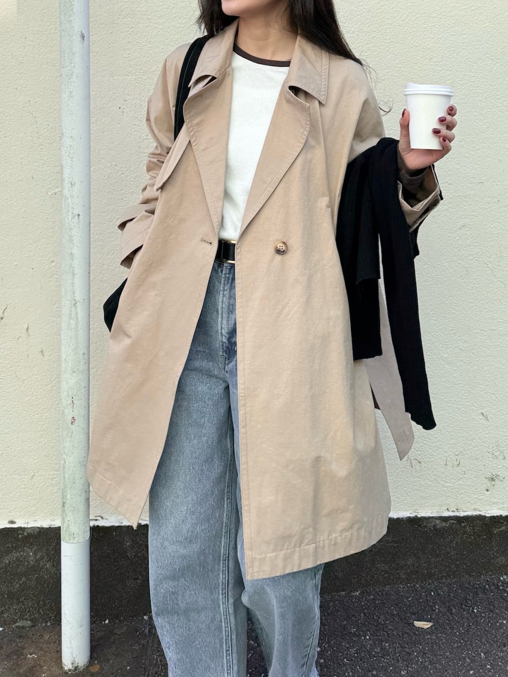 ベージュ系のトレンチコート、ブルー系のデニムパンツ、ブラック系のトートバッグを着用したレディースの冬コーディネートの3枚目の写真