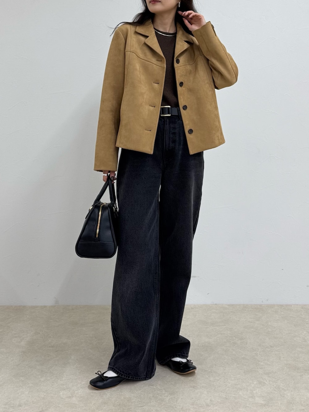 ブラック系のデニムパンツ、ベージュ系のダウンジャケット/コート、ブラウン系のニット/セーターを着用したレディースの秋コーディネートの2枚目の写真