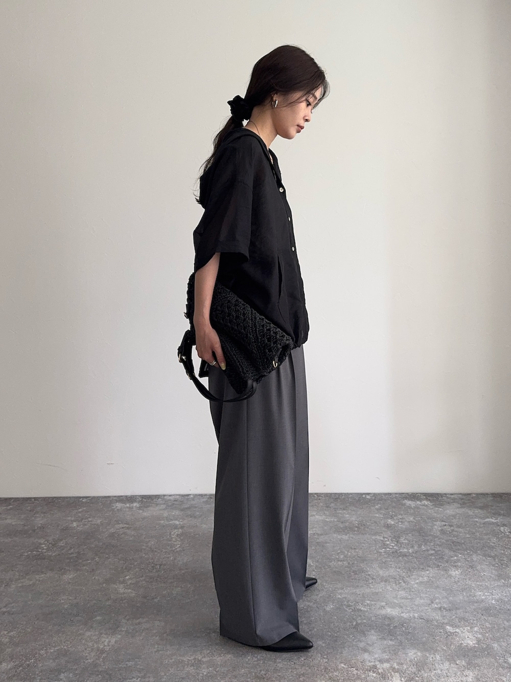 ブラック系のシャツ/ブラウス、グレー系のスラックス、ブラック系のかごバッグを着用したレディースの夏コーディネートの3枚目の写真