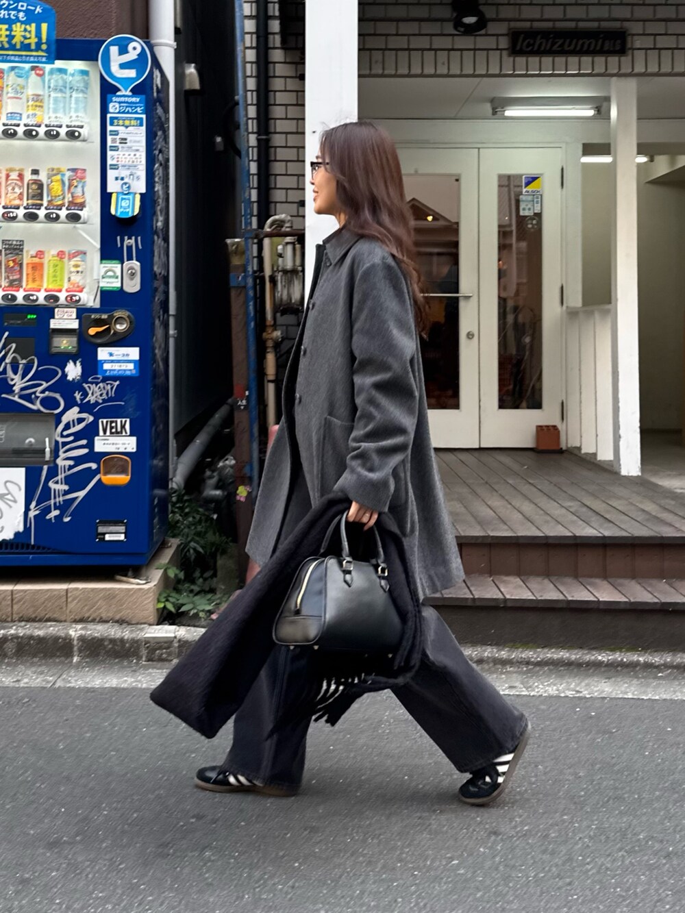 グレー系のダッフルコート、ブラック系のショルダーバッグ、ブラック系のデニムパンツを着用したレディースの秋コーディネートの2枚目の写真