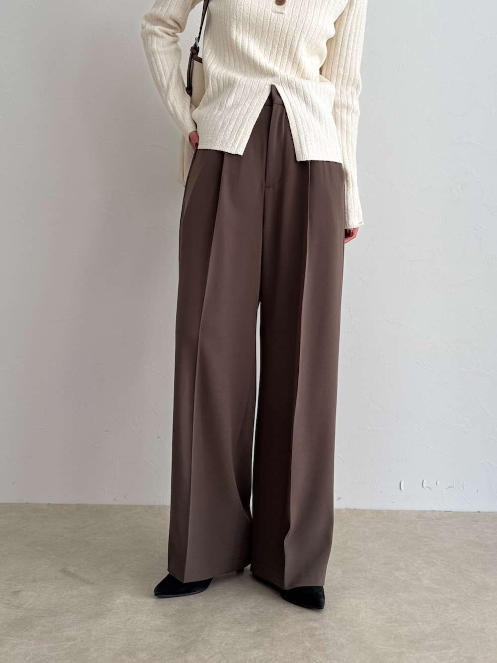 ホワイト系のニット/セーター、ブラウン系のスラックス、ホワイト系のショルダーバッグを着用したレディースの冬コーディネートの5枚目の写真