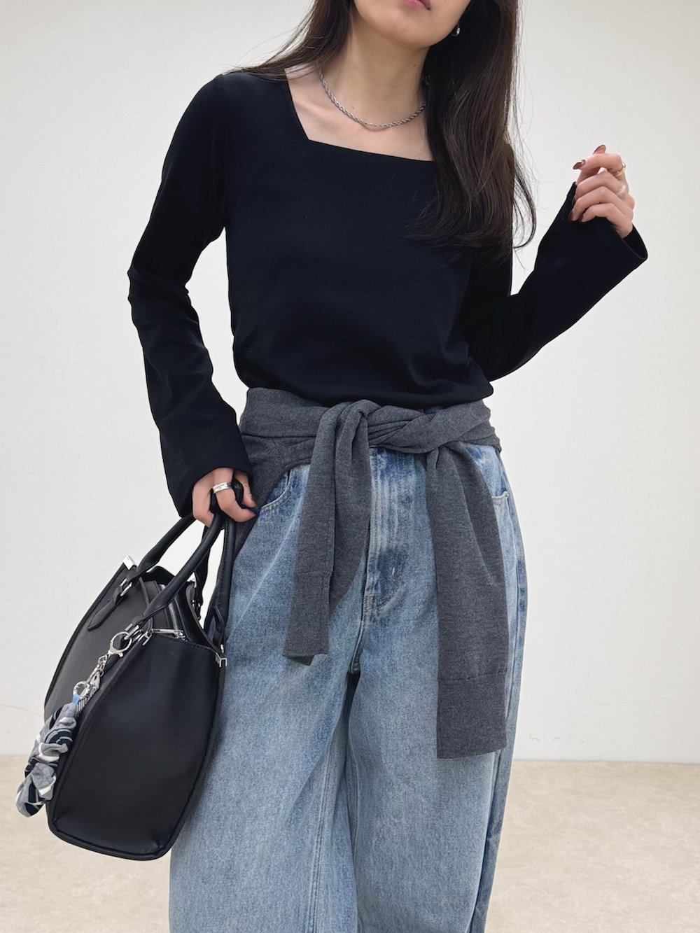 ブラック系のTシャツ/カットソー、ブルー系のデニムパンツ、ブラック系のボストンバッグを着用したレディースの秋コーディネートの6枚目の写真