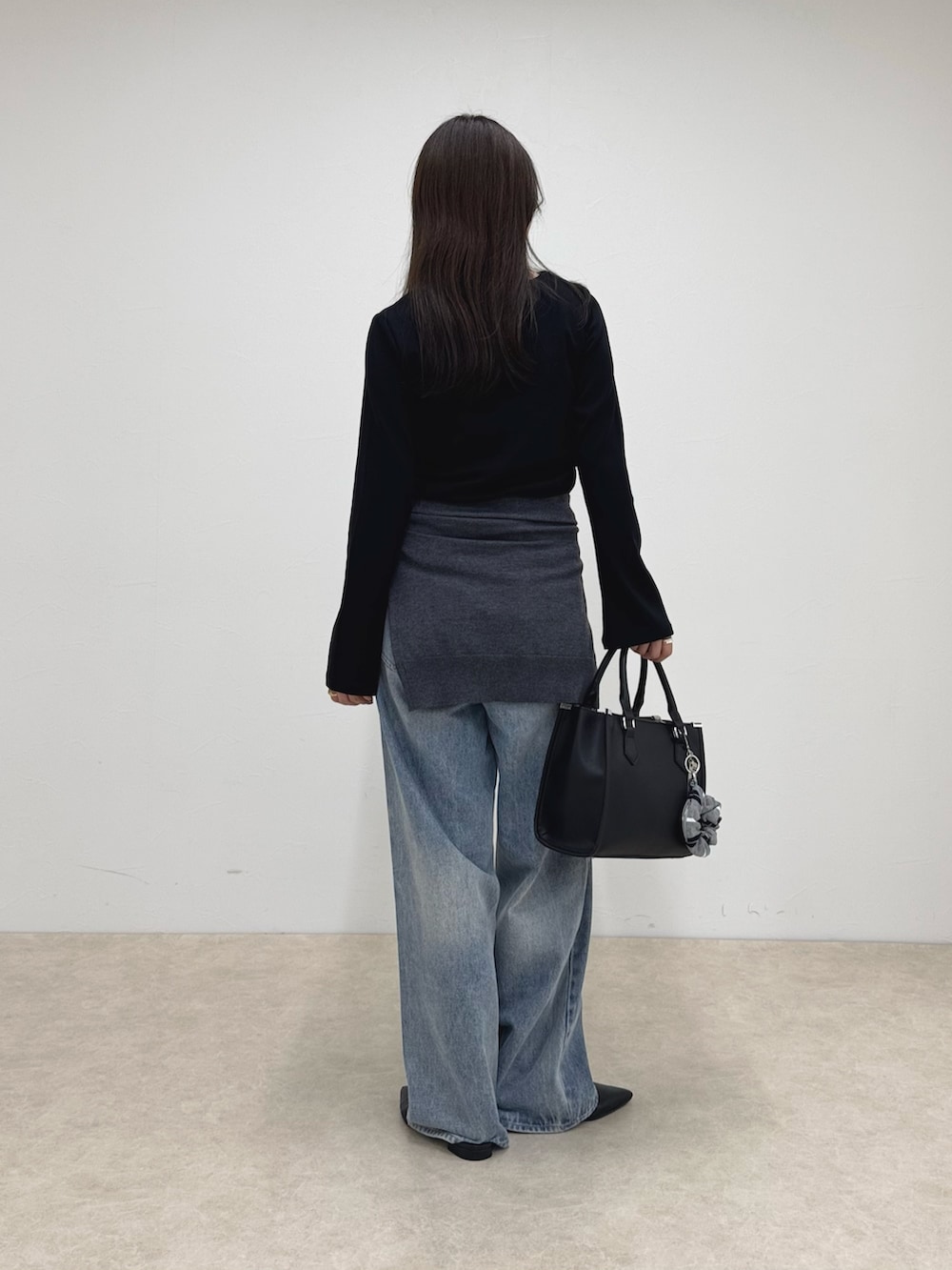 ブラック系のTシャツ/カットソー、ブルー系のデニムパンツ、ブラック系のボストンバッグを着用したレディースの秋コーディネートの4枚目の写真