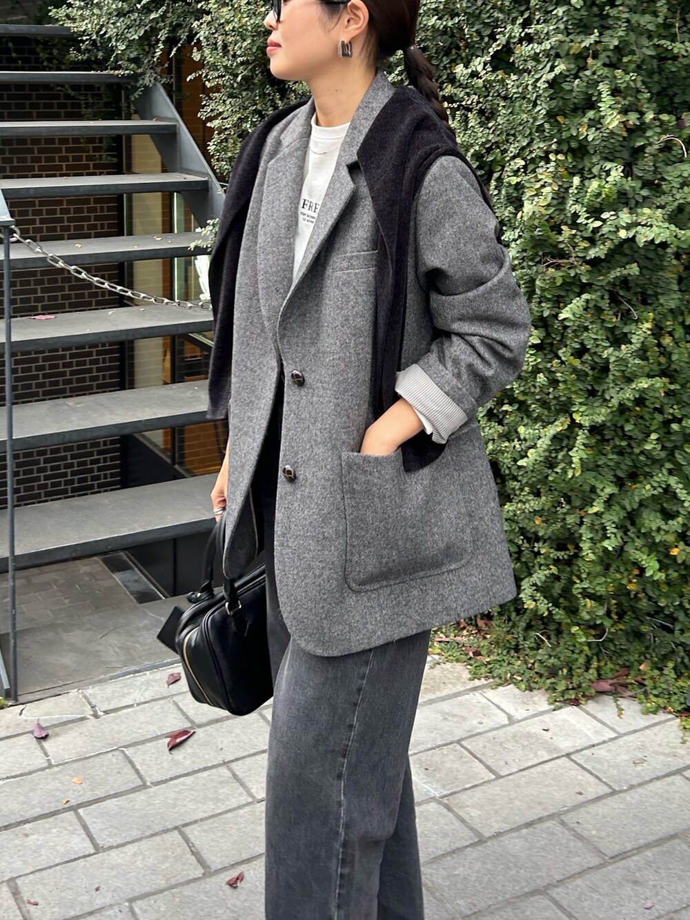 ブラウン系のテーラードジャケット、ブラック系のハンドバッグ、ブラック系のカーディガン/ボレロを着用したレディースの秋コーディネートの3枚目の写真