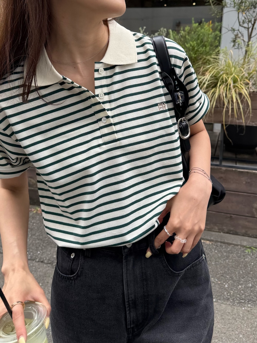 グリーン系のポロシャツ、ブラック系のデニムパンツ、ブラック系のパンプスを着用したレディースの夏コーディネートの7枚目の写真