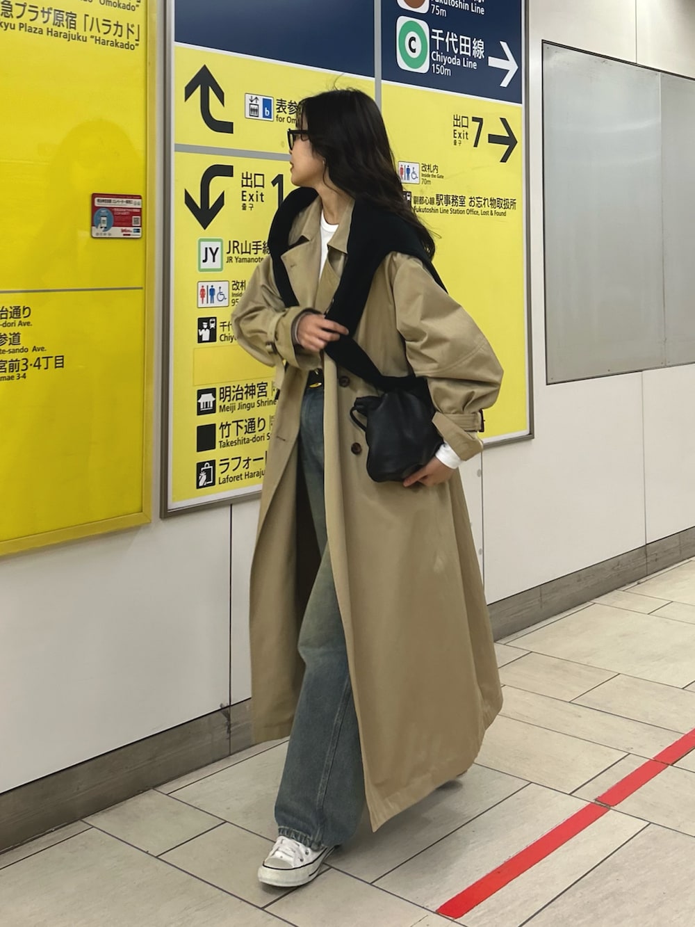 ベージュ系のトレンチコート、ブルー系のデニムパンツ、ブラック系のショルダーバッグを着用したレディースの冬コーディネートの2枚目の写真