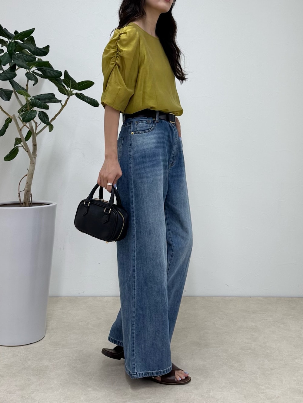 イエロー系のシャツ/ブラウス、ブルー系のデニムパンツ、ブラック系のショルダーバッグを着用したレディースの夏コーディネートの3枚目の写真