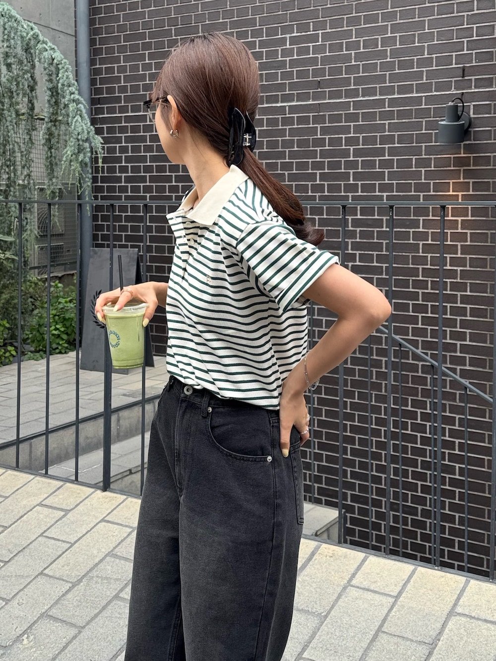 グリーン系のポロシャツ、ブラック系のデニムパンツ、ブラック系のパンプスを着用したレディースの夏コーディネートの5枚目の写真