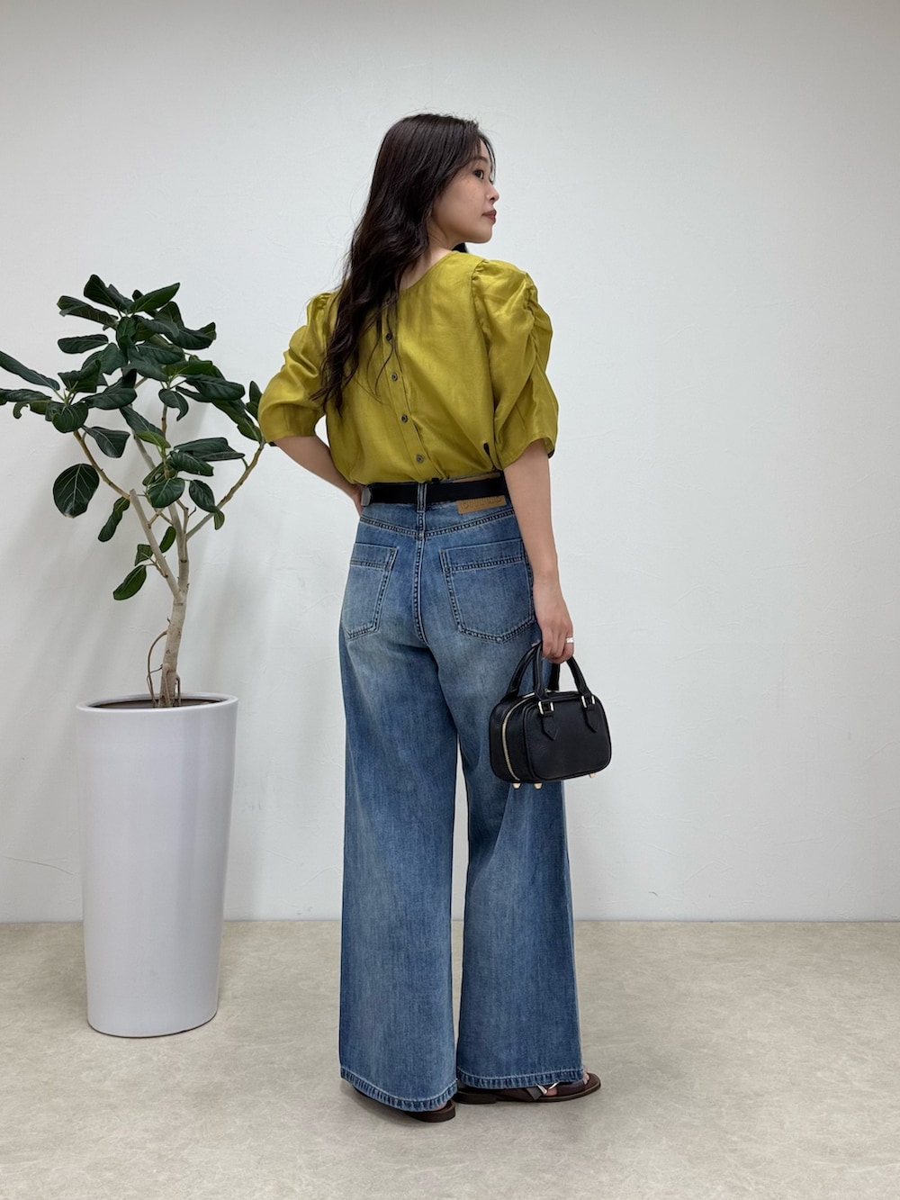 イエロー系のシャツ/ブラウス、ブルー系のデニムパンツ、ブラック系のショルダーバッグを着用したレディースの夏コーディネートの2枚目の写真