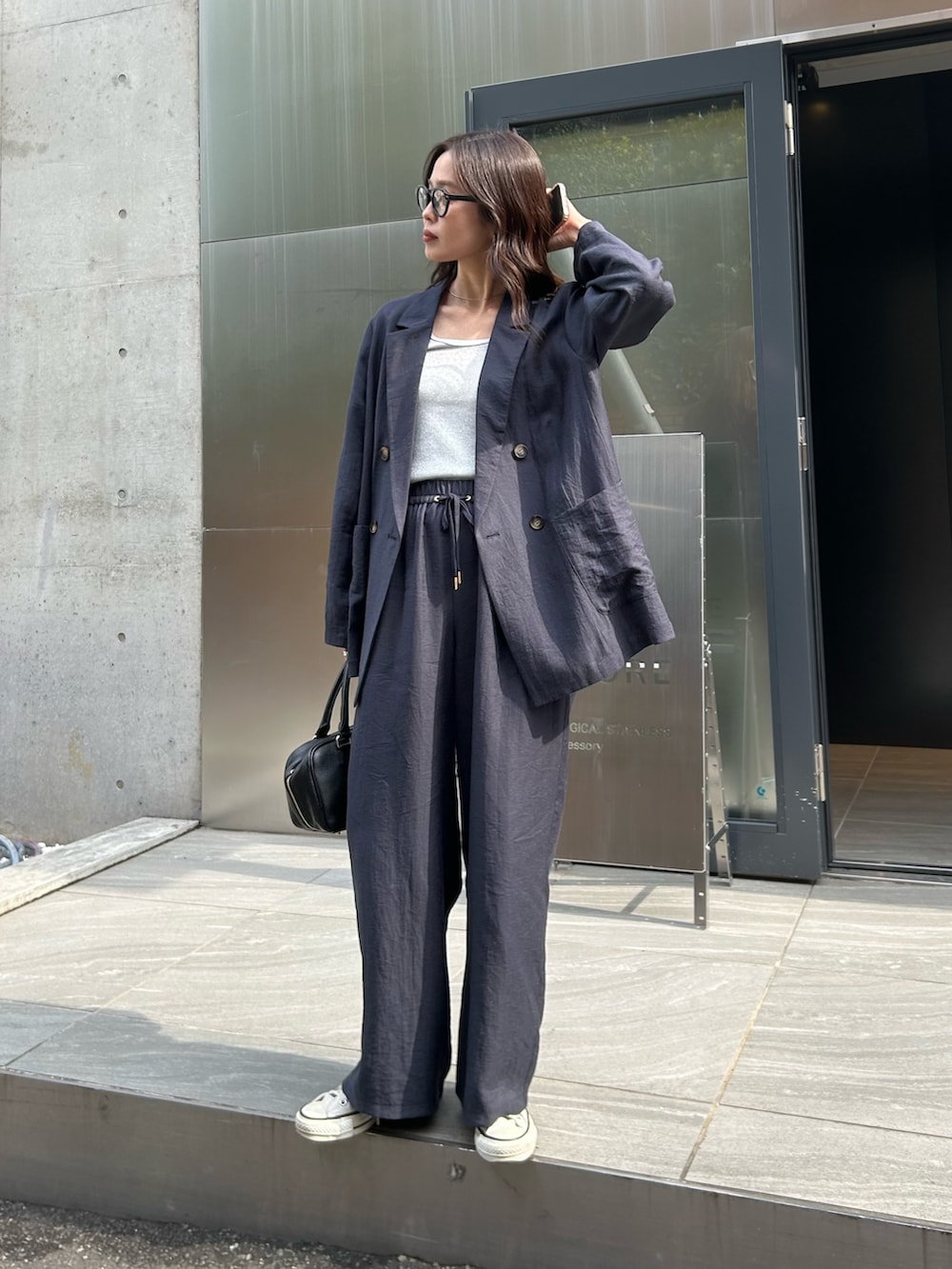 ブルー系のテーラードジャケット、ブルー系のその他パンツ、ブラック系のショルダーバッグを着用したレディースの春コーディネートの4枚目の写真