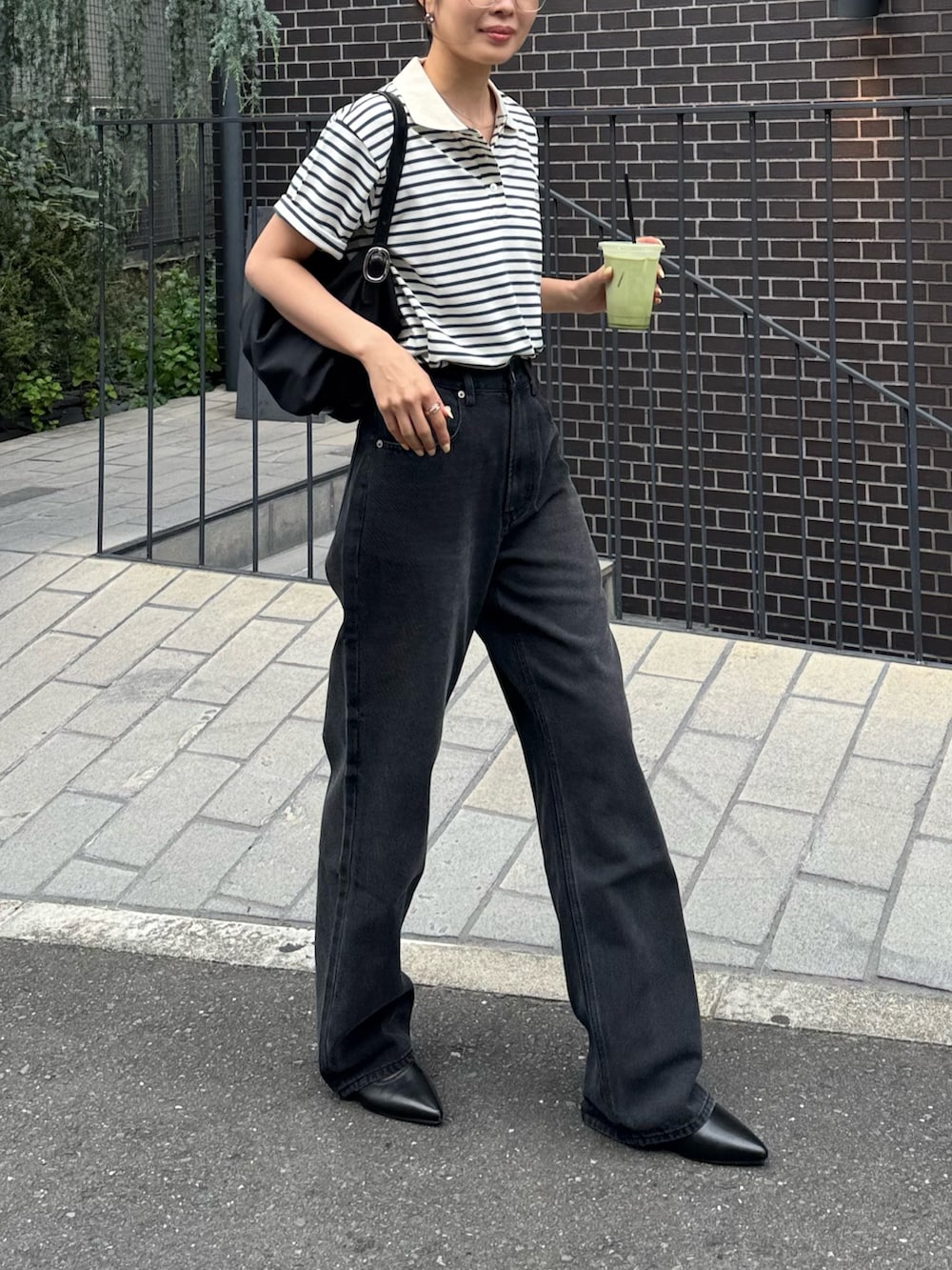 グリーン系のポロシャツ、ブラック系のデニムパンツ、ブラック系のパンプスを着用したレディースの夏コーディネートの3枚目の写真