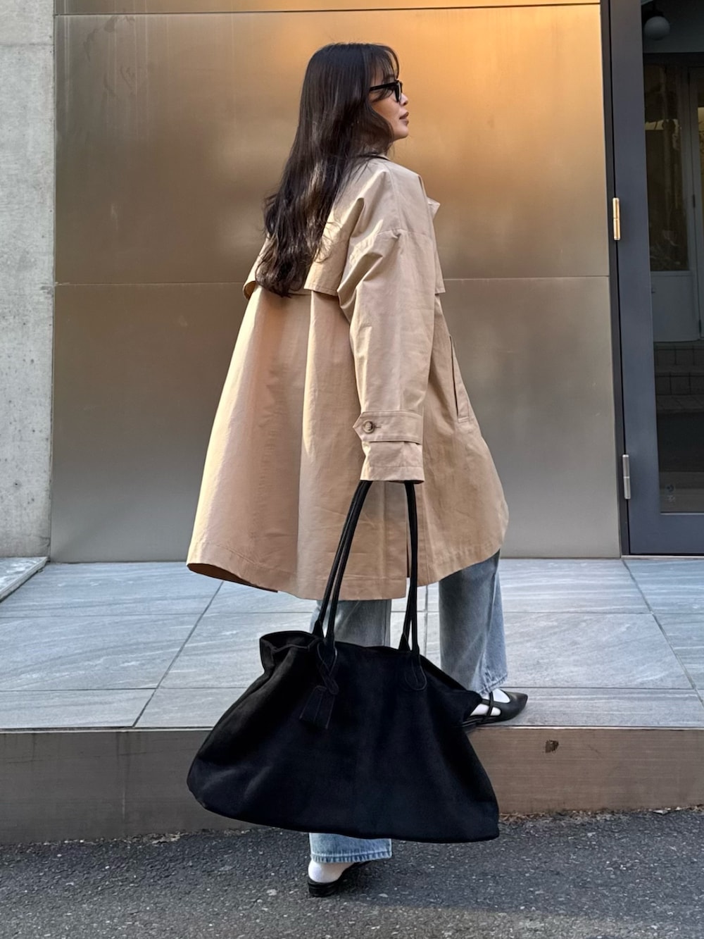ベージュ系のトレンチコート、ブルー系のデニムパンツ、ブラック系のトートバッグを着用したレディースの冬コーディネートの5枚目の写真