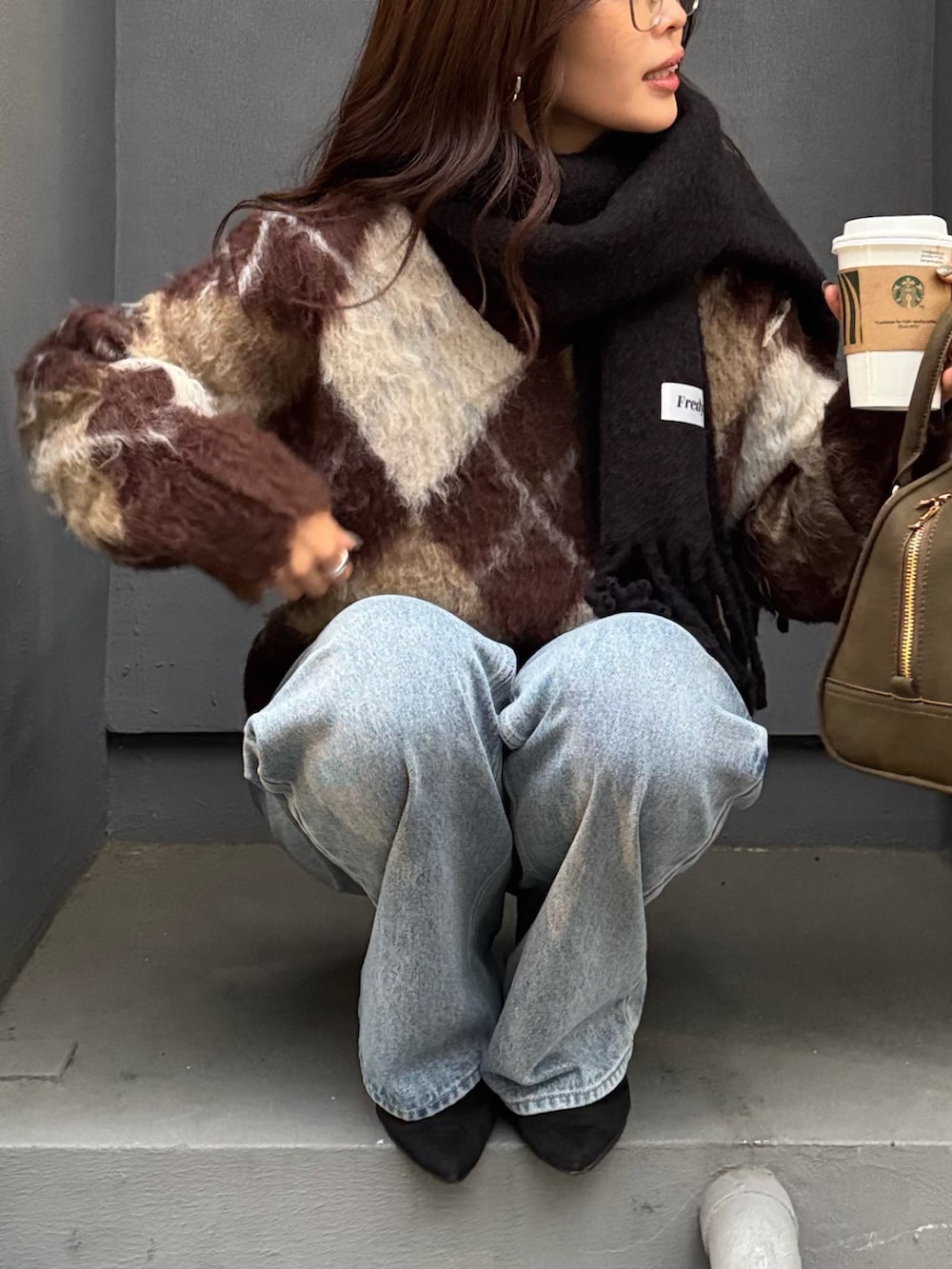 ブラウン系のニット/セーター、グリーン系のショルダーバッグ、ブルー系のデニムパンツを着用したレディースの秋コーディネートの3枚目の写真