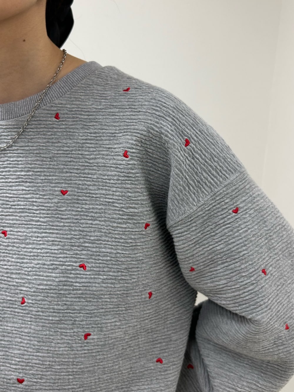 グレー系のスウェット、ブルー系のデニムパンツ、ブラック系のショルダーバッグを着用したレディースの秋コーディネートの4枚目の写真