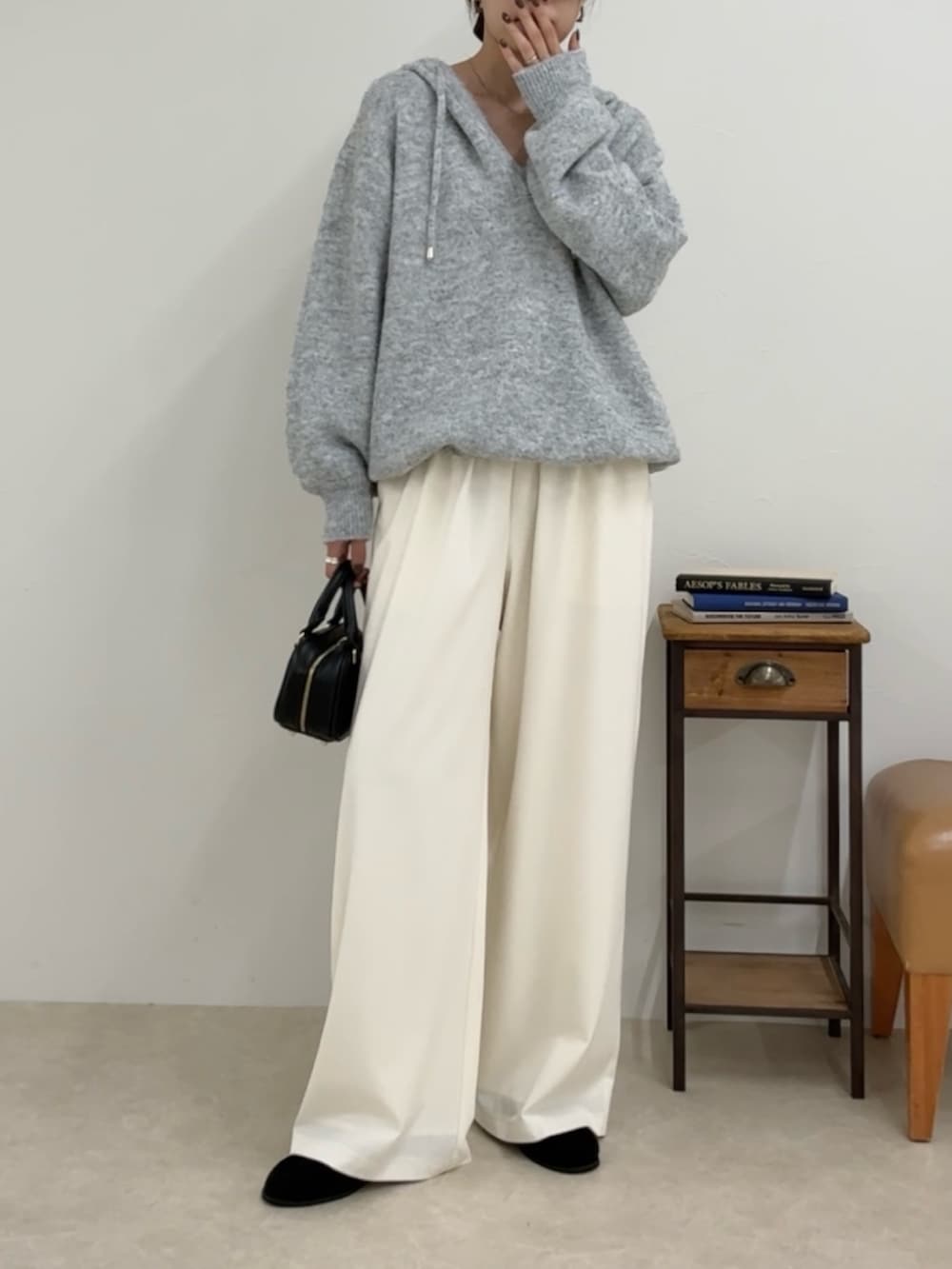 グレー系のニット/セーター、ホワイト系のその他パンツ、ブラック系のショルダーバッグを着用したレディースの夏コーディネートの2枚目の写真